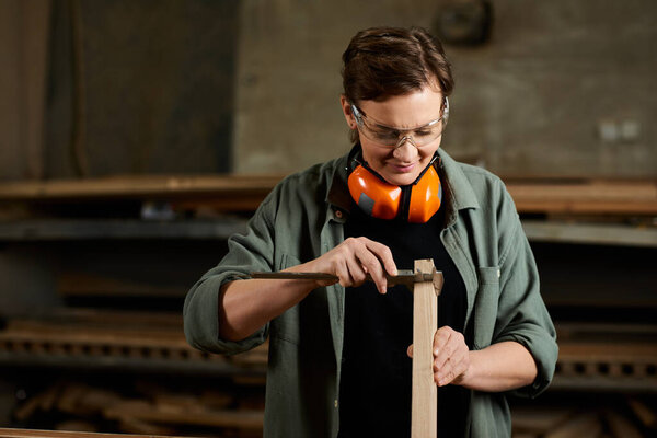 In a vibrant workshop, a female carpenter meticulously shapes wood while wearing safety gear, focused on her craft.