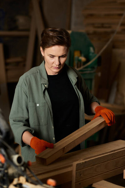 A dedicated carpenter meticulously shapes wooden pieces in her cozy workshop, showcasing craftsmanship.