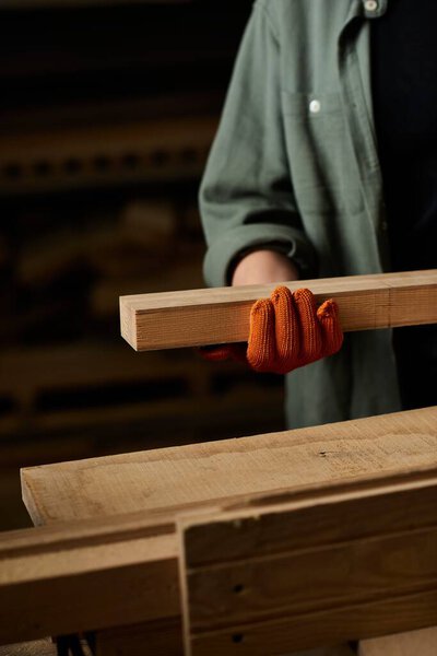 A dedicated female carpenter precisely handles wood, showcasing her craftsmanship in a vibrant workshop.