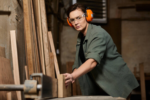 A skilled female carpenter focuses intently while crafting wood in her bustling workshop environment.