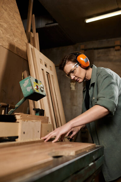 In a vibrant workshop, a talented female carpenter carefully crafts wood while wearing protective gear.