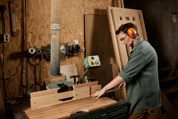 In a bustling workshop, a talented female carpenter shapes wood with tools, showcasing her craftsmanship.