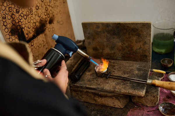 Специализированный ремесленник использует факел для расплавления металла, создавая изысканные ювелирные изделия.