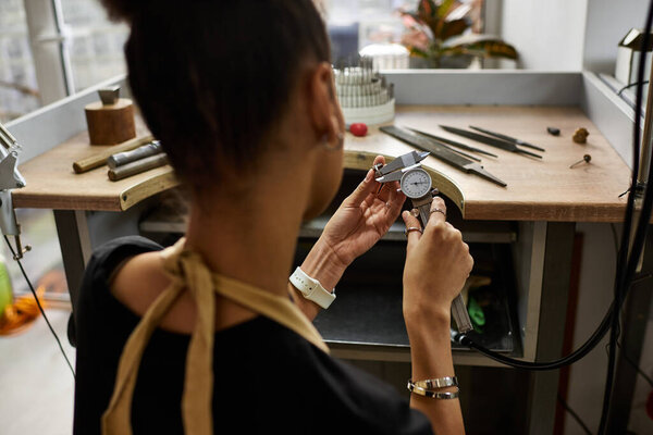 Опытный художник фокусируется на измерении драгоценных камней с точностью в яркой ювелирной студии.