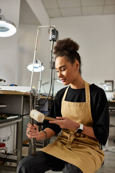 A talented artisan focuses on detailing jewelry designs while working in her workshop.