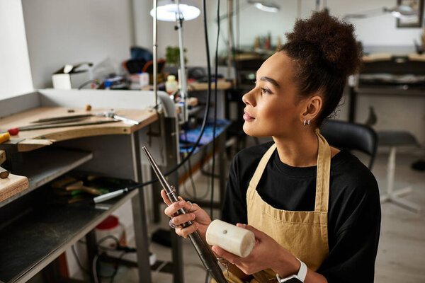 The woman attentively designs exquisite jewelry while surrounded by creative tools and materials.