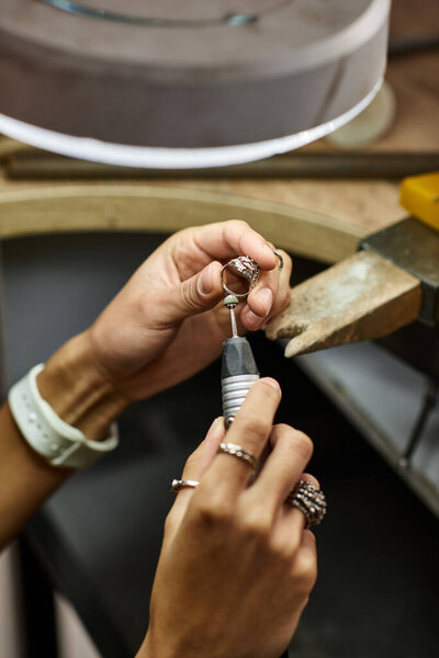 A talented woman focuses on her craft, shaping unique jewels with precision and care.