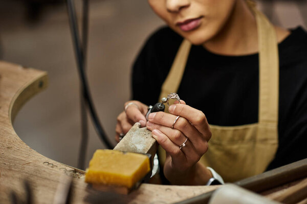 Талантливая женщина пристально следит за тем, как формирует изысканные драгоценности с помощью точных инструментов..
