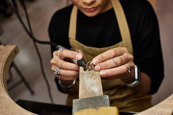 A talented jeweler intricately works on a delicate ring with precision and focus in a workshop.