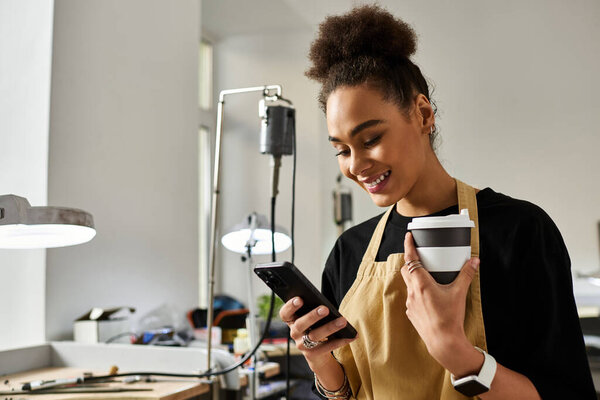 Опытная ремесленница наслаждается моментом наслаждения, общаясь с телефоном и наслаждаясь теплым напитком.