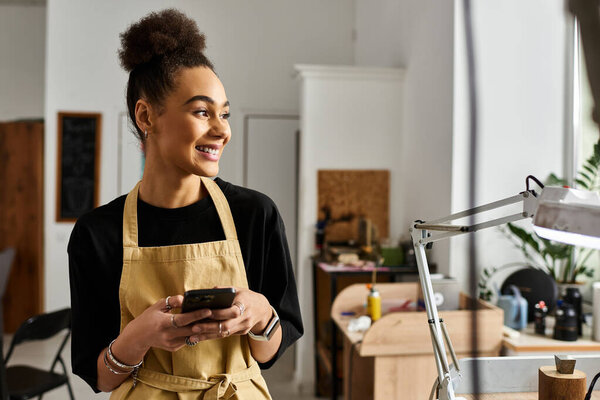A joyful woman engages with her phone, surrounded by a warm, inviting workspace.