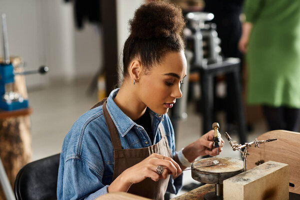 A skilled woman meticulously designs intricate jewelry while focusing intently in her workspace.