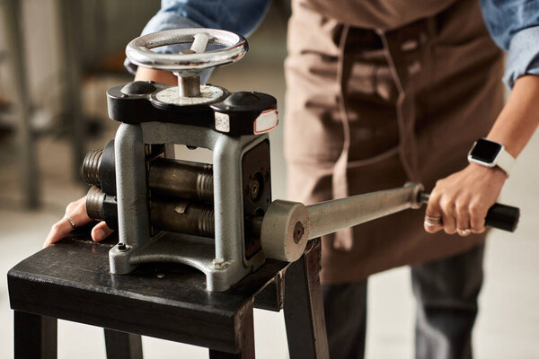 A talented creator manipulates a jewelry press, shaping beautiful designs in an artisanal setting.