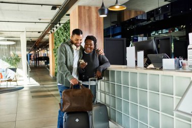 Genç bir Afrikalı Amerikalı çift otel lobisine giriş yaparken heyecanını paylaşıyor..