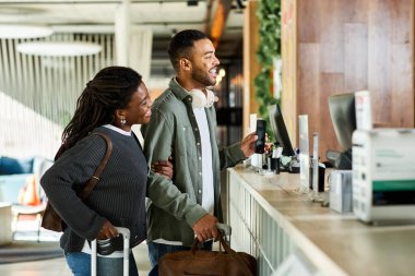 Genç bir Afrikalı Amerikalı çift, tatil kaçamakları için heyecanlı bir otel lobisine yerleşti..