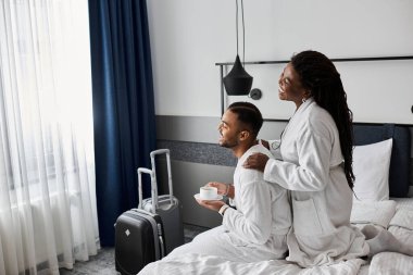 Genç bir çift şık bir otel odasında sevgi ve neşeyi kucaklıyor, birlikte huzurlu bir tatilin tadını çıkarıyorlar..