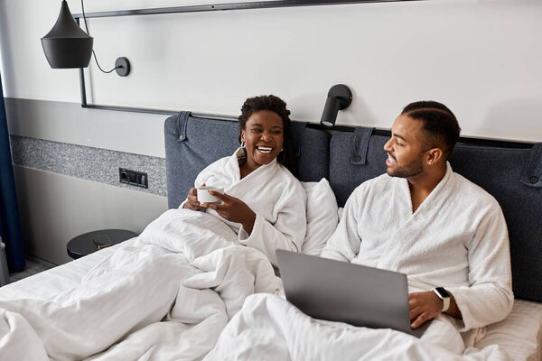 A young couple cherishes their vacation while lounging in soft robes, sharing laughter and warm moments.