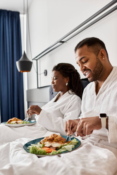 The couple, wrapped in soft robes, savors delicious meals while relaxing in their hotel retreat.