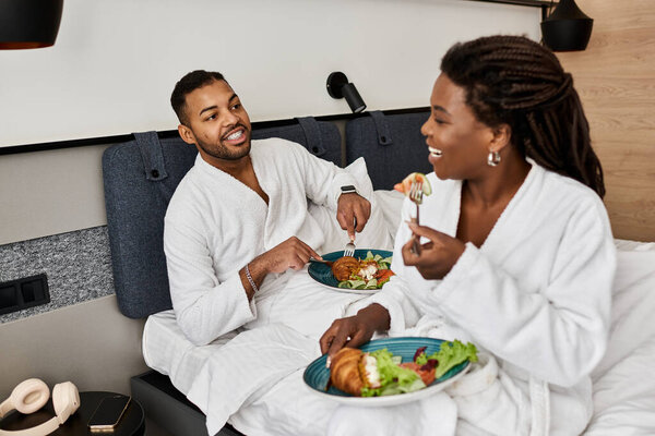 A loving couple shares a delightful breakfast in their hotel room, savoring each others company on vacation.
