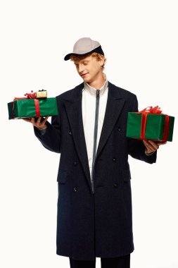 This fashionable man showcases contemporary holiday attire while joyfully holding two beautifully wrapped Christmas presents. clipart