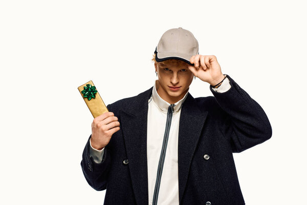 Стильный мужчина представляет тщательно завернутый подарок, источая дух праздника в модном наряде, в комплекте с кепкой. Его уверенная улыбка приглашает тепло и праздничное настроение во время Рождества 2025 года.