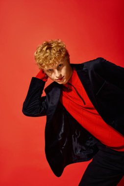 Şık bir adam çarpıcı bir kırmızı zemine karşı canlı bir tatil modası sergiliyor..