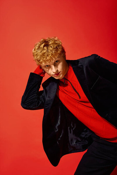 A stylish man showcases vibrant holiday fashion against a striking red backdrop.