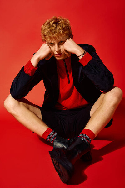 Setting the stage for Christmas 2025, a model showcases holiday fashion trends with bright hues and stylish ensembles. The striking backdrop enhances the festive atmosphere as he poses thoughtfully.