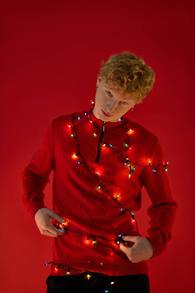 Радостный человек одет в праздничный наряд, игриво настраивая вокруг себя декоративные рождественские огни.