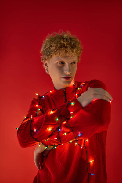 Яркая и жизнерадостная атмосфера наполняет воздух, когда модный мужчина позирует в красном наряде, украшенном разноцветными рождественскими огнями. Этот модный вид захватывает радость курортного сезона 2025 года.