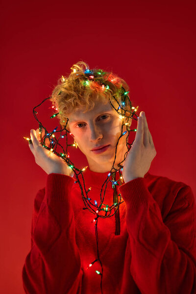 Человек демонстрирует свою уникальную праздничную моду, игриво переплетаясь в яркие рождественские огни.