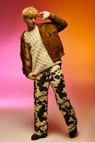 Мужчина уверенно позирует в ярком праздничном наряде, смешивая уютный вязаный свитер с жирными коровьими узорчатыми брюками.