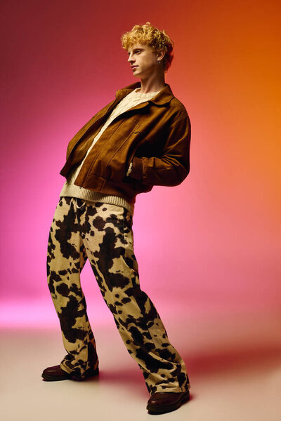 Стильный мужчина демонстрирует смелый праздничный вид на Рождество 2025 года с коричневой курткой и яркими штанами для печати коровы. Яркий фон усиливает праздничную привлекательность его наряда.