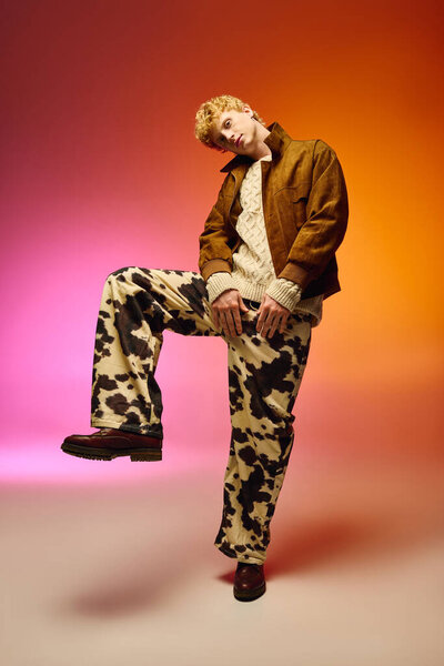 Мужчина уверенно стоит в ярком праздничном ансамбле, с коровьими штанами для печати и уютным вязаным свитером. Художественное освещение добавляет праздничного штриха, делая этот момент незабываемым.