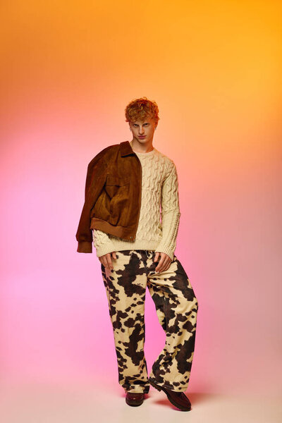 Мужчина демонстрирует творческую праздничную моду с уютным свитером и поразительными узорчатыми брюками, источая праздничные вибрации на ярком фоне в духе Рождества 2025 года.