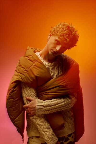 Стильный мужчина демонстрирует творческий праздничный наряд, смешивая уютные текстуры с жирными цветами. Он уверенно носит вязаный свитер и драпированный фугу, воплощая современные рождественские флюиды в 2025 году..