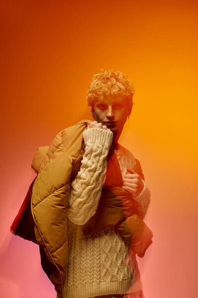 Молодой человек демонстрирует свою праздничную моду в уютной обстановке, смешивая текстуры с шикарным трикотажным свитером и современным пиджаком. Теплые тона создают праздничное настроение, идеальное для Рождества.