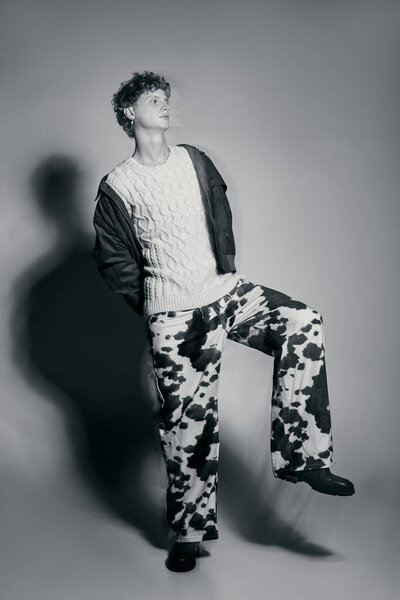 Мужчина уверенно стоит в поразительном наряде, который сочетает праздничную моду с художественным чутьем. Его толстый вязаный свитер идеально сочетается с привлекательным взглядом, коровьими шрифтами, излучающими уникальный стиль.