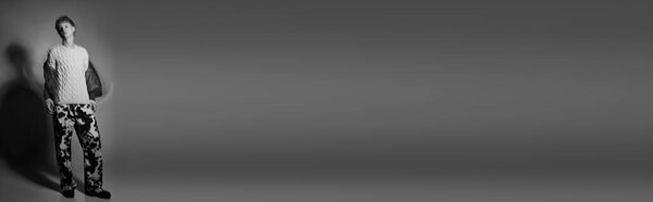 Стильный мужчина демонстрирует современную праздничную моду с уютным вязаным свитером и яркими узорчатыми брюками.