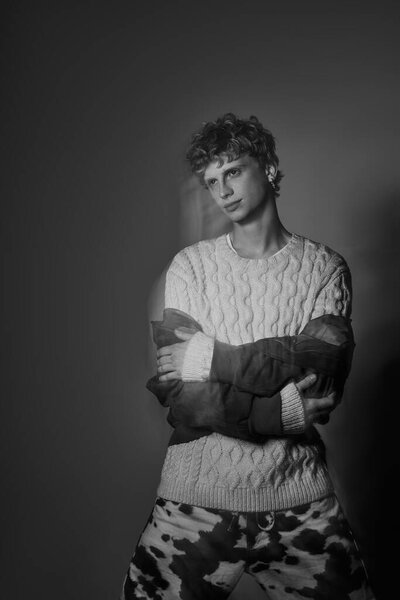 Модный человек уверенно стоит в современной обстановке, демонстрируя уникальную смесь праздничного наряда.