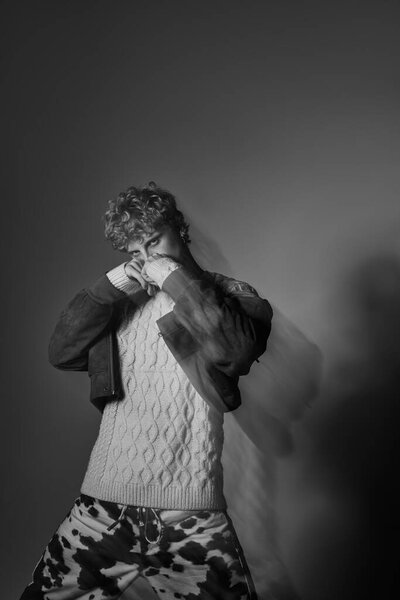 Молодой человек демонстрирует модную праздничную моду с уютным вязаным свитером и уникальными узорными брюками. Его уверенная поза источает праздничный дух Рождества 2025 года.