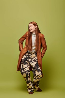 Duygusal genç adam kendine has tarzını, uzun kızıl saçlarıyla canlı bir arkaplanda sergiliyor..