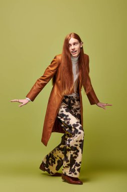 Duygusal olarak dışavurumcu genç adam uzun kızıl saçlı ve desenli pantolonlu moda anlayışı sergiliyor..