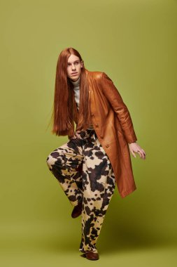 Duygusal genç adam eşsiz moda anlayışını çarpıcı yeşil bir ortamda sergiliyor.