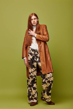 Uzun kızıl saçlı genç adam derin duygular sergiliyor. Eklektik moda modelliği yapıyor..