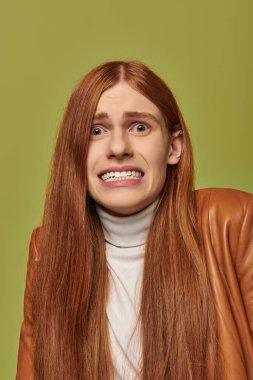 Young man with long red hair shows an emotional expression against a vivid backdrop. clipart