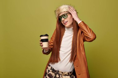 Uzun kızıl saçlı genç bir adam elinde kahve fincanı tutarken duygularını ifade eder..