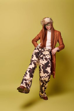 Aydınlık bir ortamda, uzun kızıl saçlı genç bir adam moda yoluyla duygusal tarzını sergiliyor..