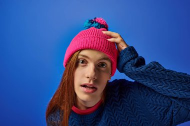 A young man showcases his emotions while posing against a bright blue background. clipart