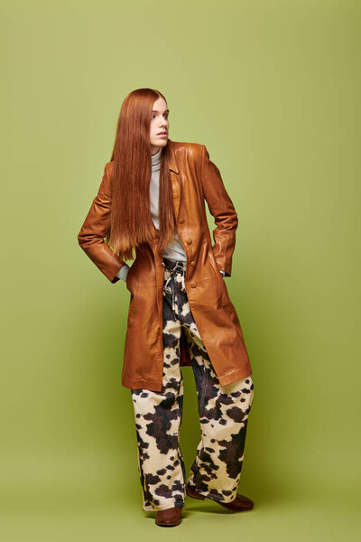 Confident young man with long red hair shows off his style against a vibrant backdrop.